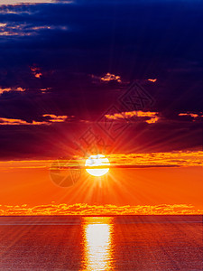 日落时暗云中太阳和海水表面的全景高清图片