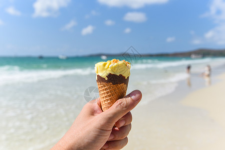 夏季天气炎热的海滩上融冰淇淋海洋景观自然户外度假黄冰淇淋芒果与坚冰淇淋锥与海背景齐头并进背景
