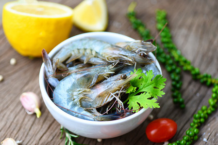白碗新鲜虾和木制底配有食用海产品生虾的饲料草药和香高清图片