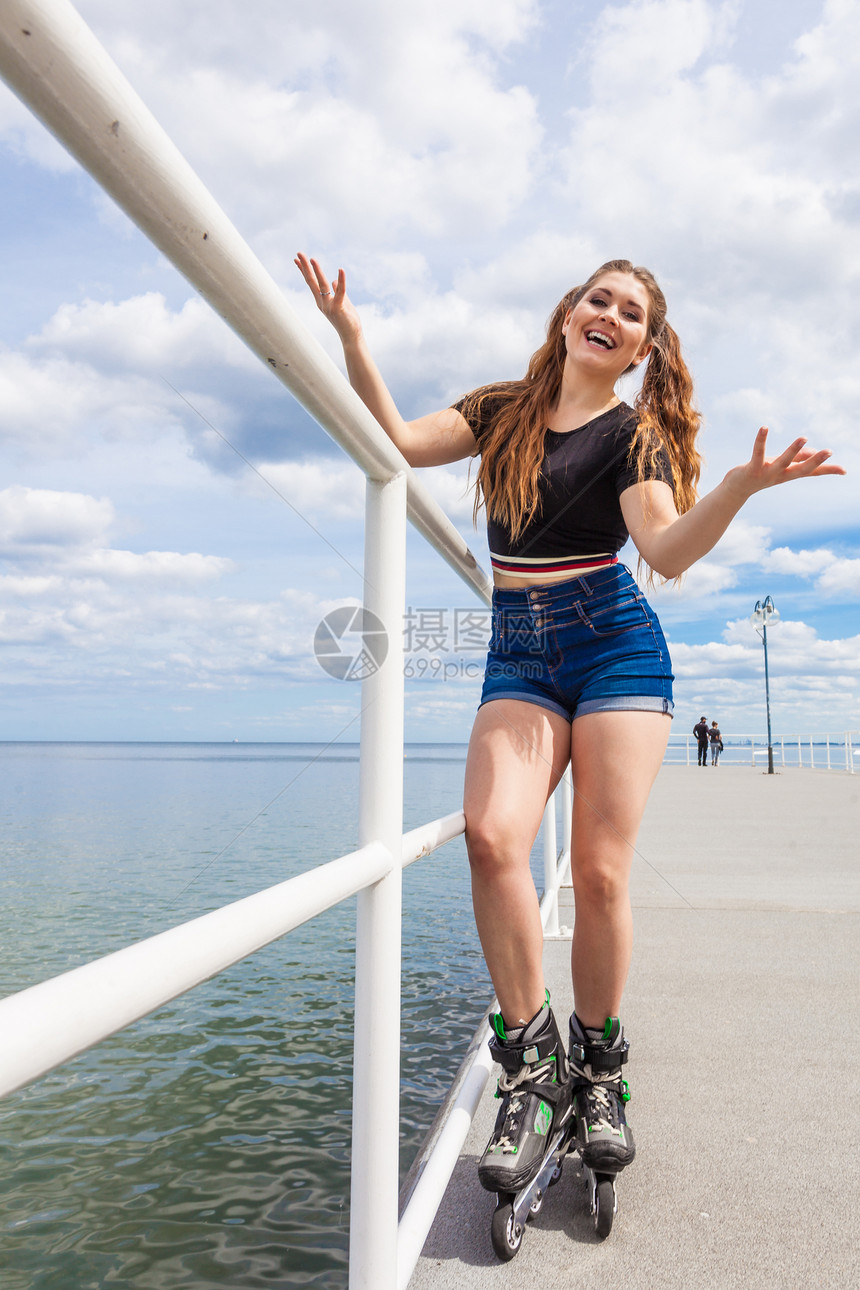 快乐的年轻女子在海上穿滑冰鞋女孩在夏天玩得开心快乐的少女穿滑冰鞋图片