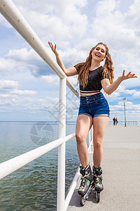 快乐的年轻女子在海上穿滑冰鞋女孩在夏天玩得开心快乐的少女穿滑冰鞋图片