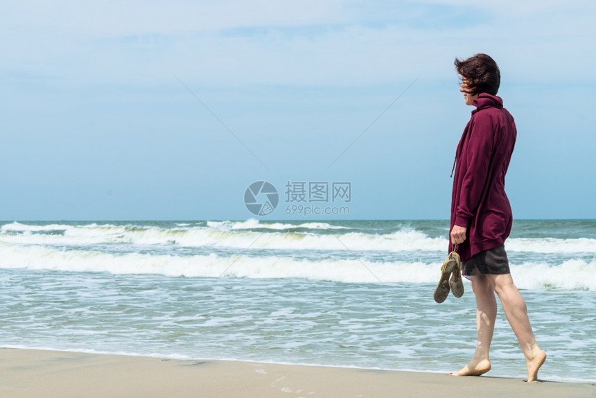 妇女在海滩上赤脚行走图片
