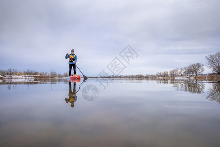 在科罗拉多州初春一名高级男护甲手站在桨板上科罗拉多州一名高级男护甲手在幼年春起踏板上背景图片