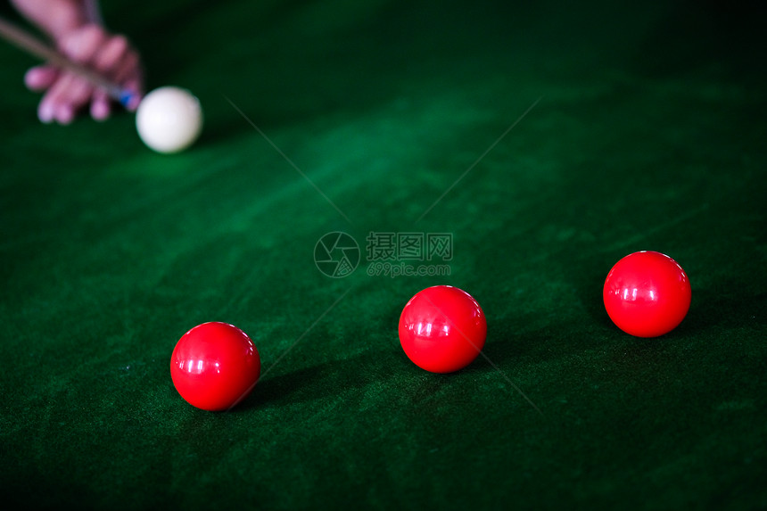 Man手和Cue臂在玩Snooker游戏或准备在绿色球桌上绿色盘上有多彩的Snooker球图片