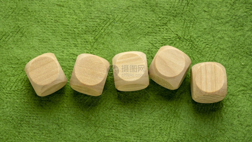 绿色手工树皮纸上的一排空白木骰子立方体工艺概念图片