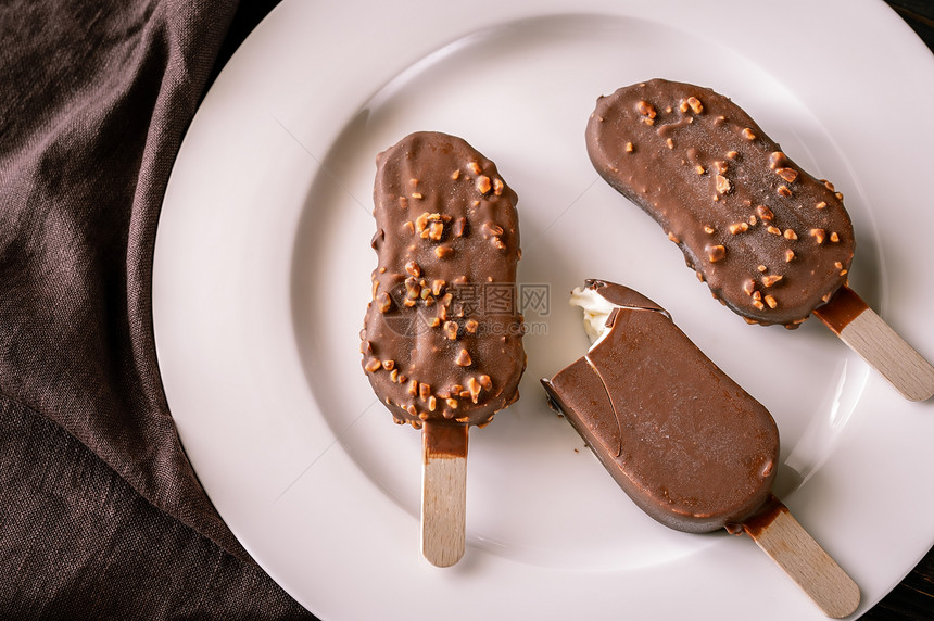 巧克力覆盖的香草冰淇淋白盘上的冰淇淋棒图片