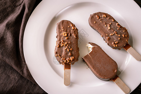 巧克力覆盖的香草冰淇淋白盘上的冰淇淋棒图片