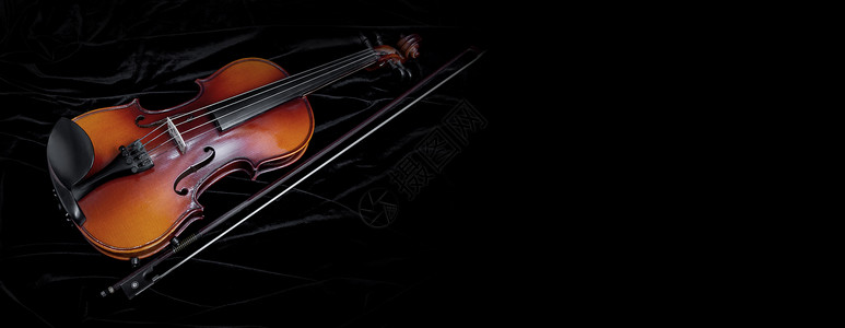 用黑色天鹅绒背景与复制空间隔离的闪亮小提琴和弓图片
