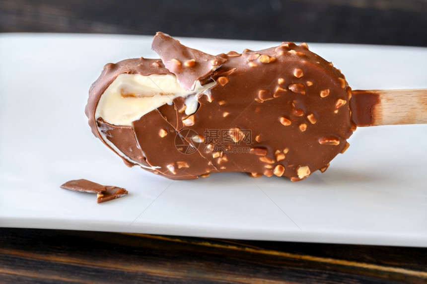 巧克力覆盖香草冰淇淋棒在白盘上图片