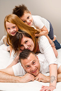 微笑的一家人躺在床上玩得开心图片