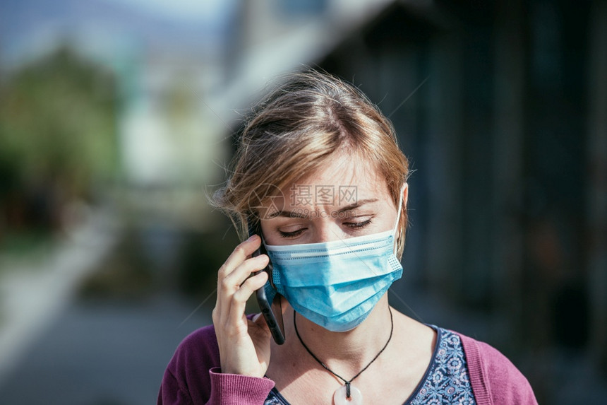 外出穿面罩和智能手机的年轻女子科罗纳和流感季节图片