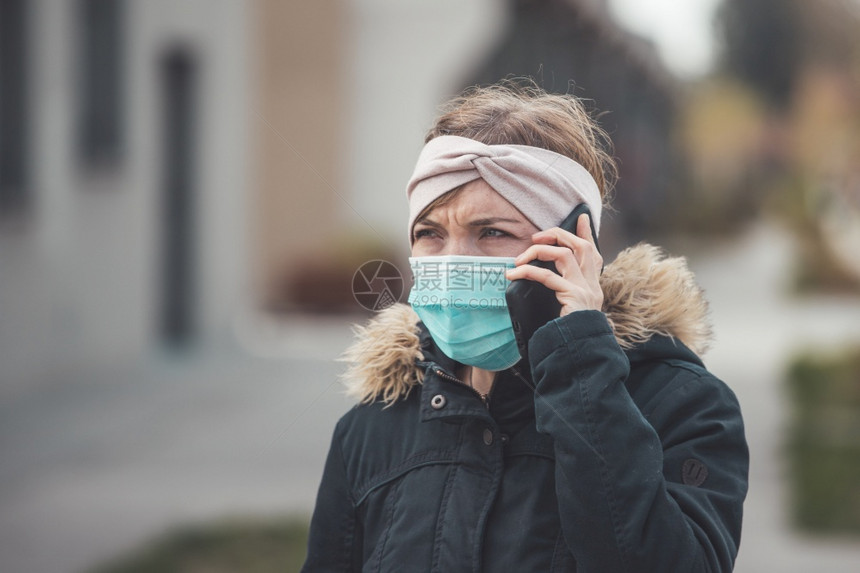 外出穿面罩和智能手机的年轻女子科罗纳和流感季节图片