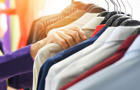 男时装服挂衣着彩色或柜架服颜色不同的男子服装衣在商店或展厅的衣架上柜背景图片