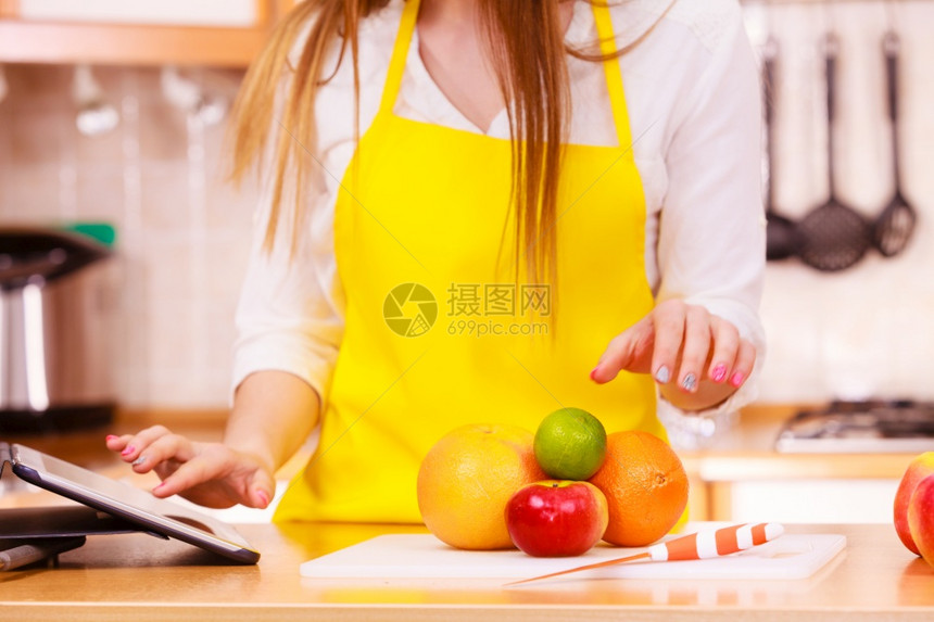 厨房女年轻家庭主妇许多水果在餐桌上用平板电脑看食谱健康饮烹饪素饮和技术概念厨房女家庭主妇用平板电脑看水果图片