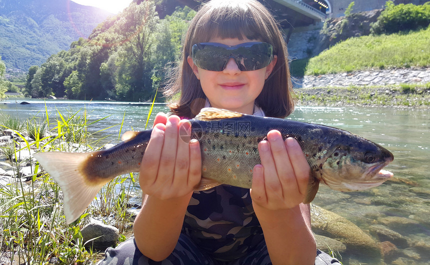 年轻女孩在河里钓鳟鱼图片
