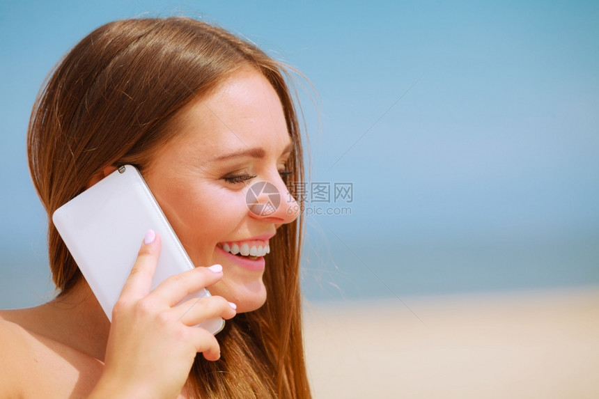 科技与交流快乐的微笑女人手机给朋友打电话年轻有魅力的女孩在海滩上用智能手机说话图片
