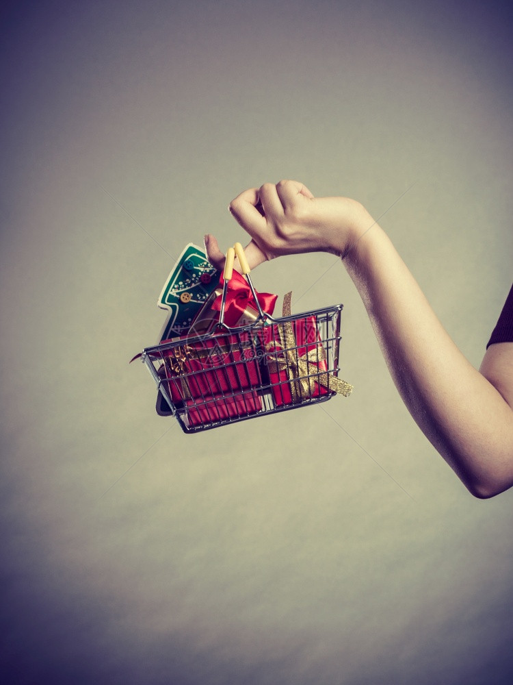 圣诞节季节销售冬庆祝活动概念妇女手拿着购物车篮子里面有小圣诞树和礼物图片