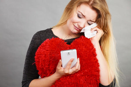 悲伤的心碎女人哭着看她的手机悲伤心碎女人看着她手机图片