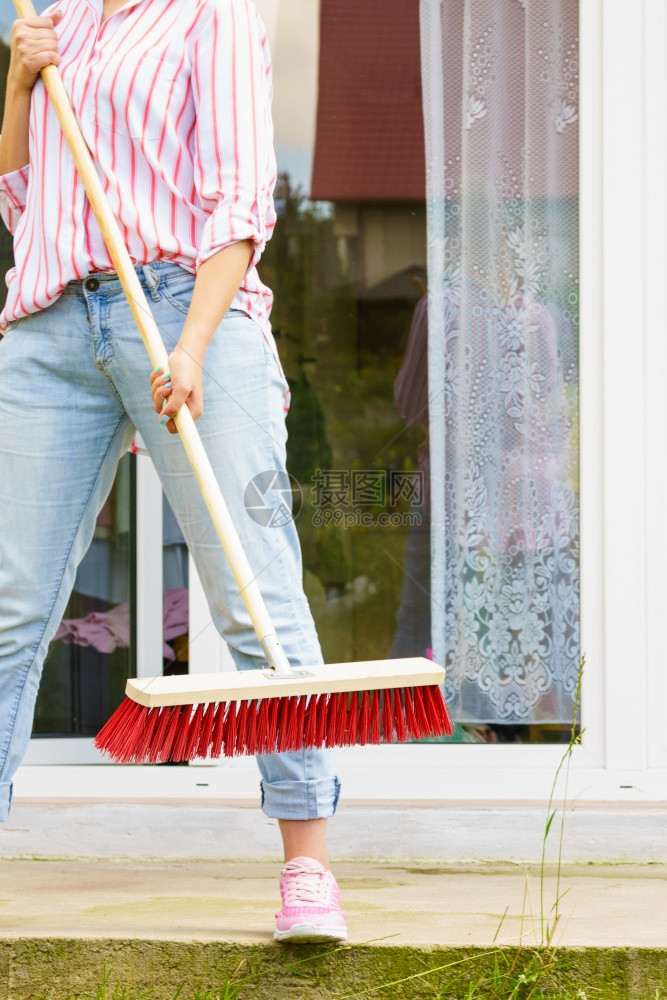 使用大扫帚清理后院子的妇女使用扫帚清理后院子的妇女图片