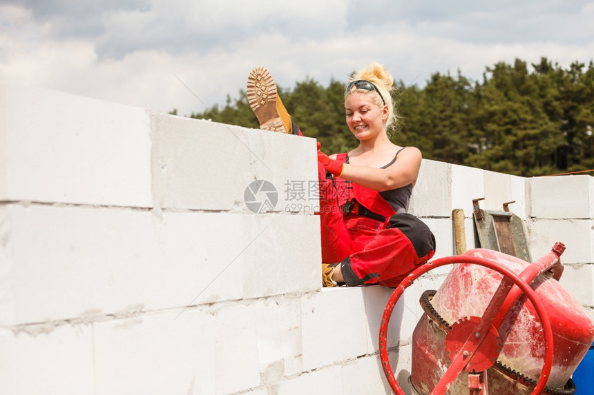 在房屋建筑工地使用红水泥混凝土搅拌机的强力女工图片