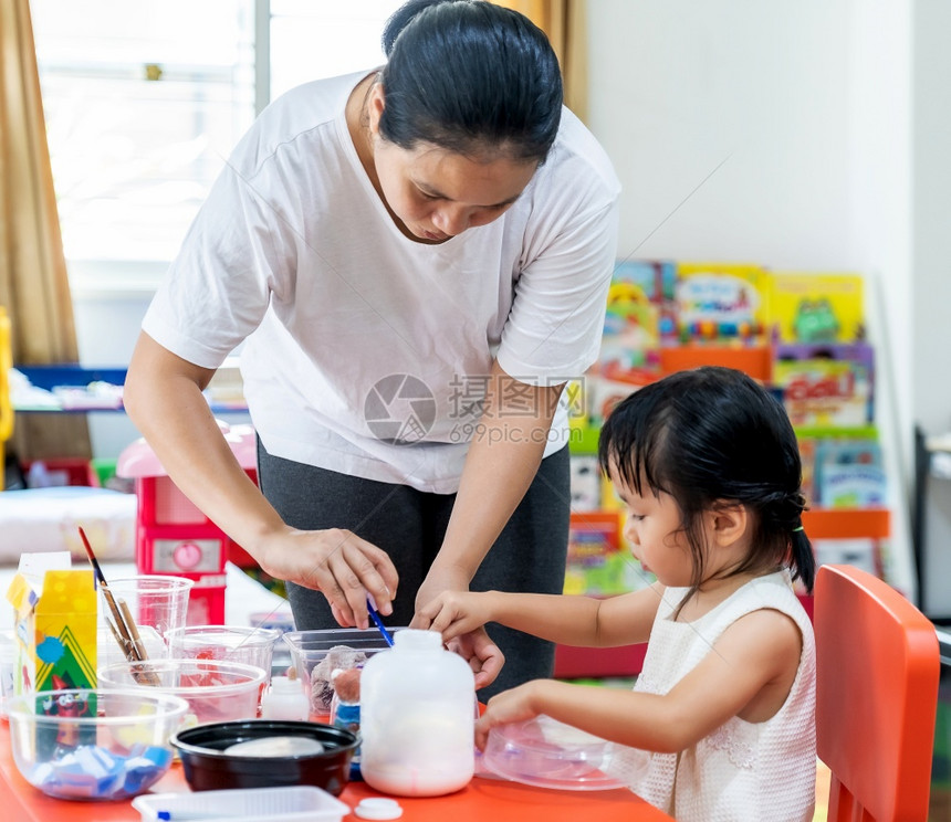 亚洲女孩玩具和彩色纸在家里客厅上艺术课在家里上学而城市封锁是因为世界各地以四胞胎妈为老师图片