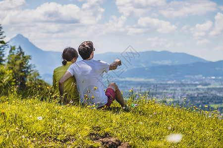 来远足旅行的夫妇坐在草地上享受远城风景高清图片