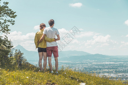 高山症夫妇徒步旅行站在草地上享受远城风景背景