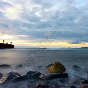日落的海景水在运动中模糊海滩上有石块码头渔民大西洋特内里夫岛图片