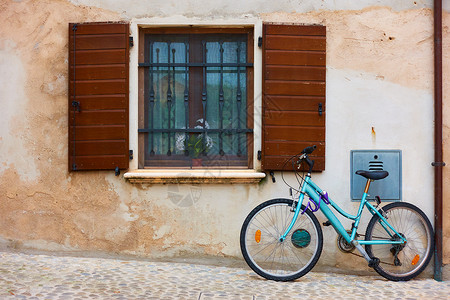 埃米利娅罗曼尼亚在意大利EmiliaRomagna一个小意大利城镇的旧房子墙附近的街道上自行车窗子和开着的左轮手在意大利EmiliaRomagn背景