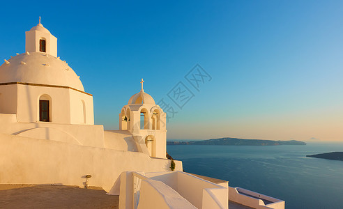 希腊山托里尼岛悬崖上的希腊教堂日落时离海边风景图片