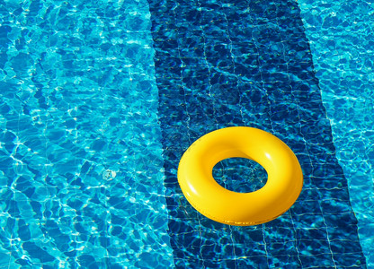 黄色游泳池漂浮环在清新蓝色游泳池里图片