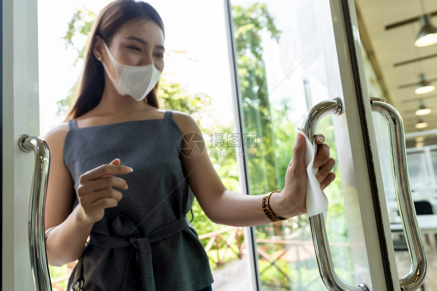 手紧的亚洲女手用纸把餐厅门打开减少手触碰公共场所以减少感染新冠共食19的机会图片