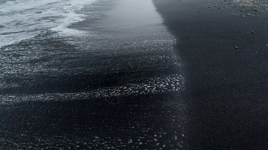 海洋滩上湿黑色火山砂的近抽象图像图片
