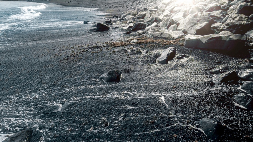 黑色火山海沙滩和蓝色浪上闪耀着明日的海景黑色火山海沙滩和蓝色洋浪上闪耀着明日的海景图片