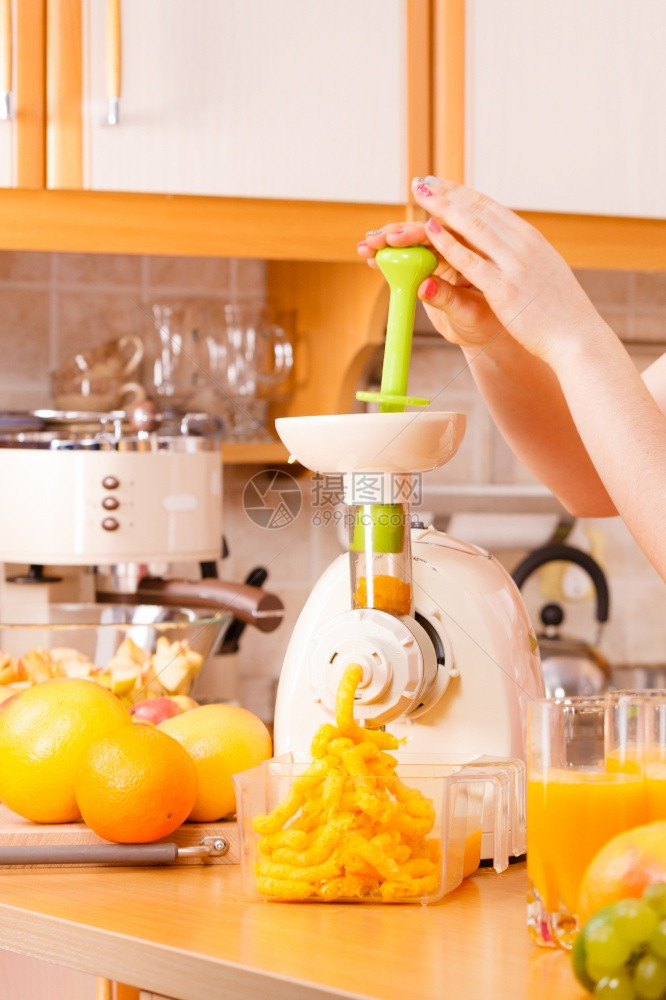 厨房的年轻女家庭主妇在果汁机中制造新鲜橙汁准备营养的维他命包装饮料健康食素和人的概念图片