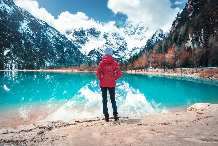 穿着红色夹克的年轻女子站在湖岸边秋天意大利多洛米特的Dolomites图片