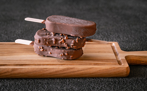木板上杯巧克力覆盖的香草冰淇淋棒图片