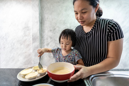 亚洲女孩与母亲一起做鸡蛋煎饼面包店儿童家务使发挥行政功能图片