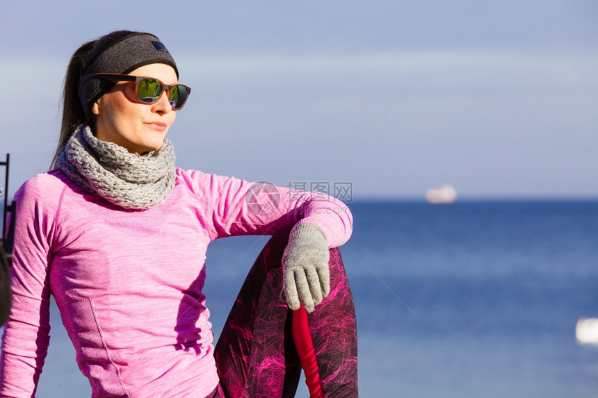 女子在户外运动后休息健身女运动员在寒冷的天气中穿着温暖运动服在海边休息女子在寒冷的户外运动后休息图片