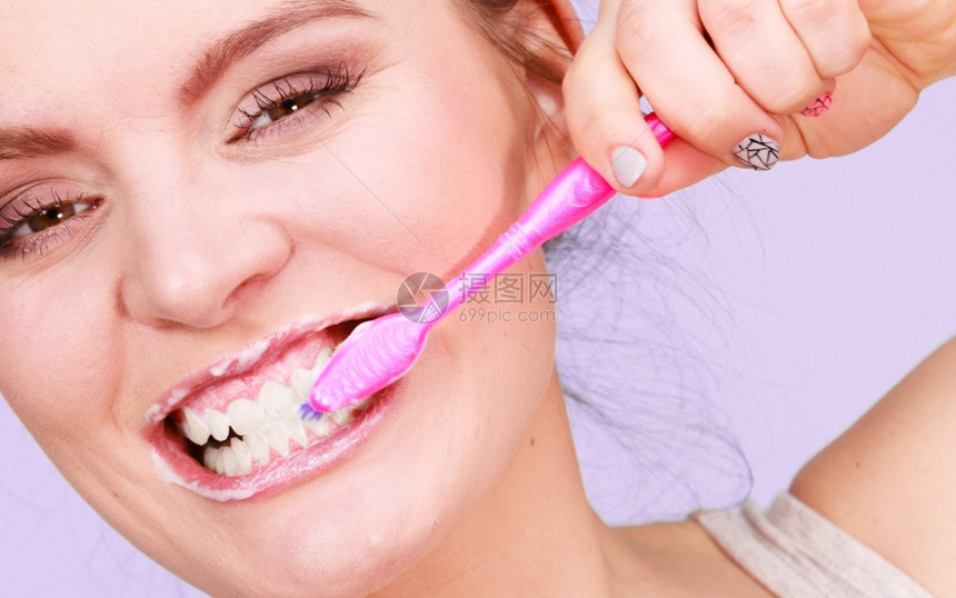 妇女刷牙口腔卫生亮紫色背景图片