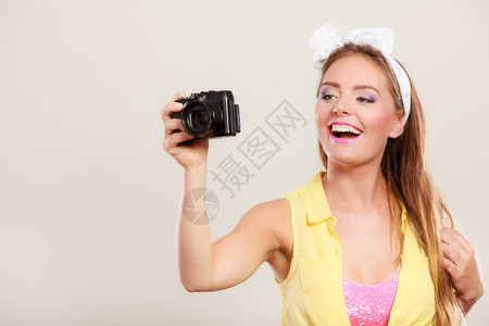 笑的漂亮女孩带着发弓拿相机拍照图片