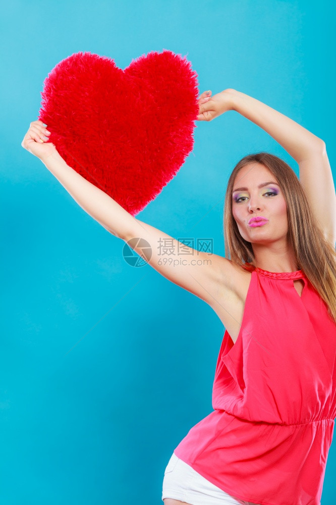 穿着红心型枕头的漂亮可爱年轻女孩在工作室蓝发之吻情人节的爱图片