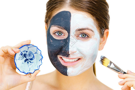 白泥涂在干净的皮肤上女孩照顾油色的皮肤美容程序皮肤护理黑脸涂在白色的上背景