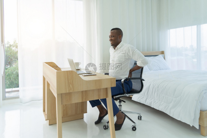 疲劳的黑人美国非洲患有背痛或抽筋使用电脑笔记本电脑长时间坐在椅子上背痛肌肉疼办公室综合症图片