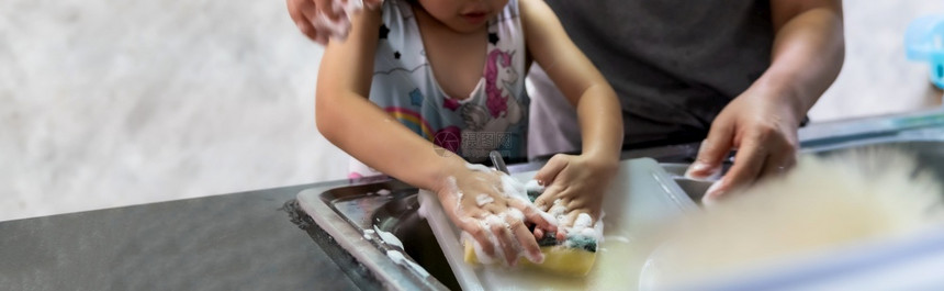 Asian女孩与母亲一起洗碗和餐具儿童家务使发挥执行职能图片