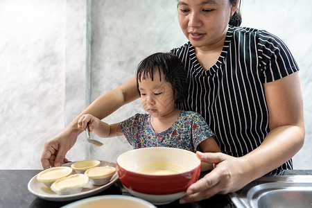 亚洲女孩与母亲一起做鸡蛋煎饼面包店儿童家务使发挥行政功能图片