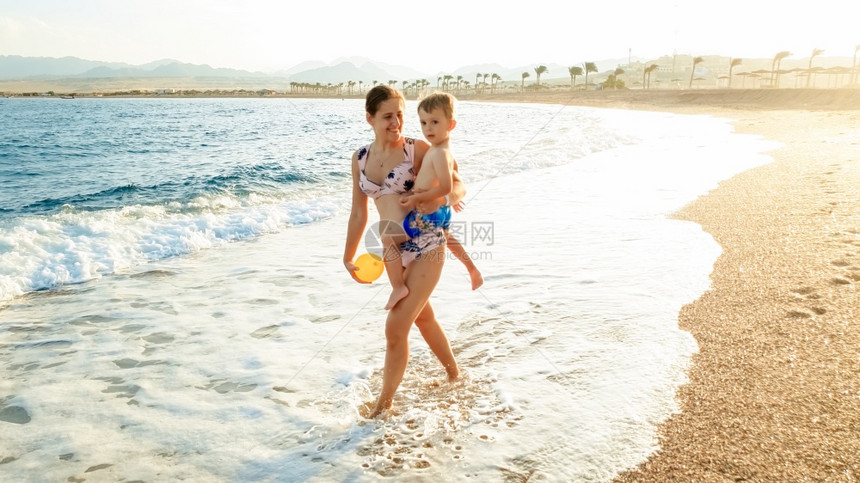 母亲在沙滩上抱着儿子散步图片