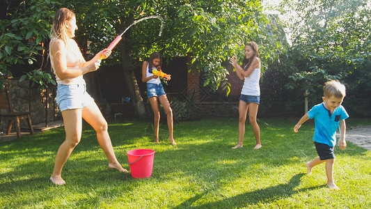 家庭夏季在户外玩耍和乐家庭夏季在后院玩耍时快乐儿童用水和花园龙头玩耍跳高清图片素材