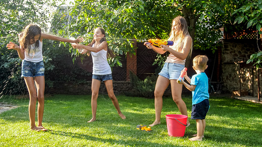 有趣的是在炎热阳光天家庭快乐儿童玩水软管高清图片素材