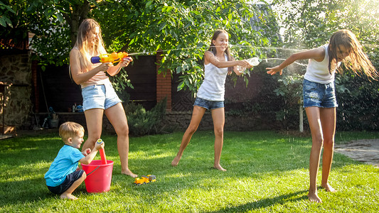 家庭夏季在户外玩耍和乐家庭夏季在后院玩耍时快乐儿童用水和花园龙头玩耍图片